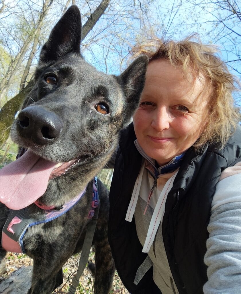 Nő és boldog brindle kutya szelfi erdőben.